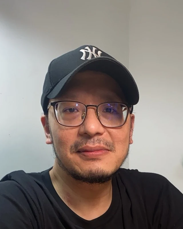 Joe in a cap and glasses, smiling.